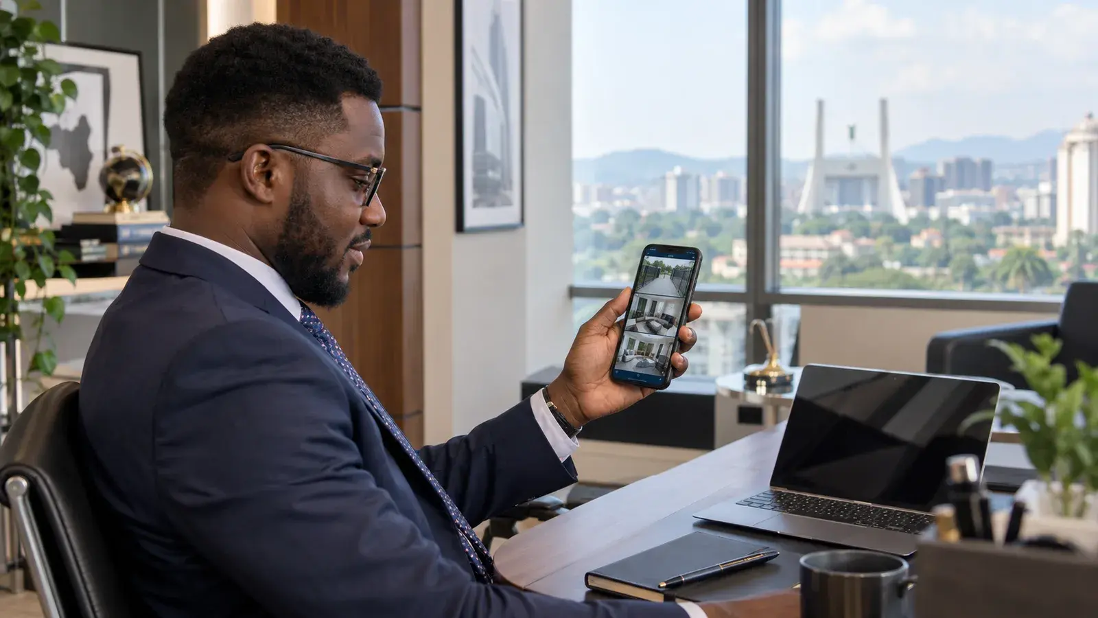 A businessman in an Abuja office checking live CCTV camera feeds on his phone